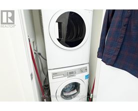 A white washing machine with a red handle is in a small space.