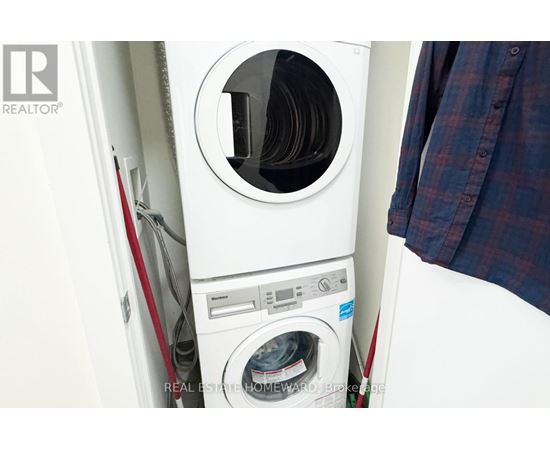 A white washing machine with a red handle is in a small space.