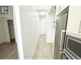 A kitchen with a refrigerator and oven in a hallway.