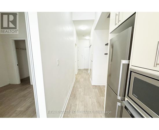 A kitchen with a refrigerator and oven in a hallway.