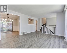 A spacious living room with a staircase leading to the upper floor.