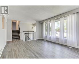 A spacious room with wooden flooring and a staircase leading to another level.