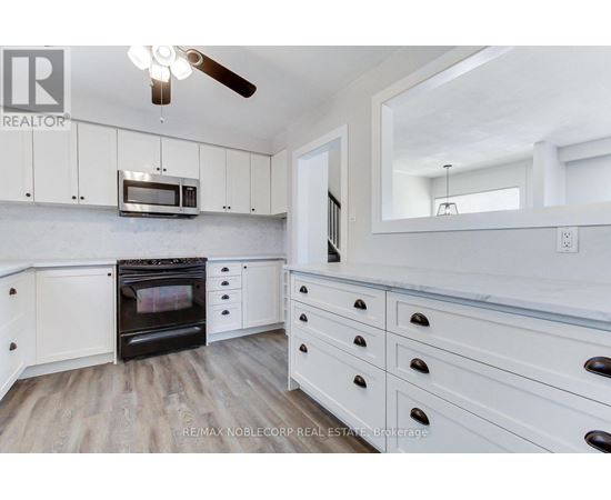 A kitchen with white cabinets and a wood floor.