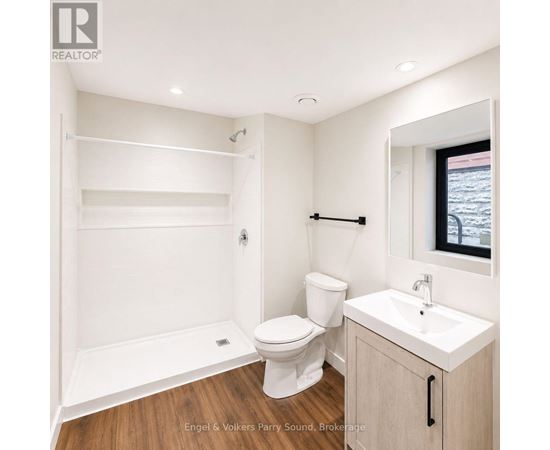 A white bathroom with a toilet, sink, and a mirror.