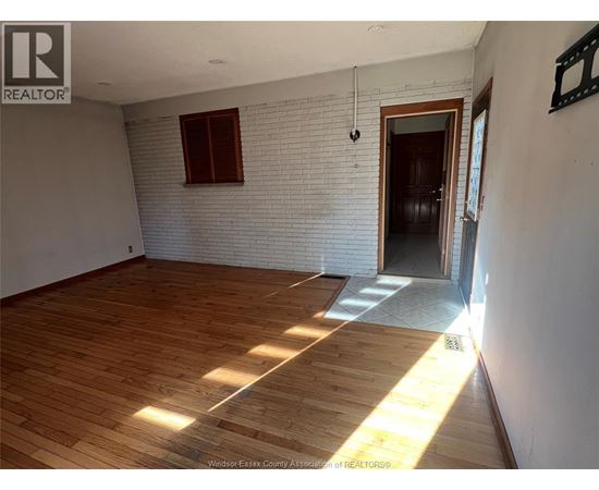 A room with wooden flooring and a white brick wall.