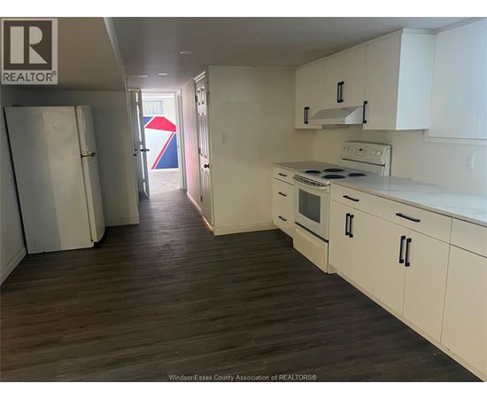 A kitchen with white cabinets and a wooden floor.