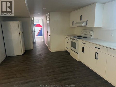 A kitchen with white cabinets and a wooden floor.
