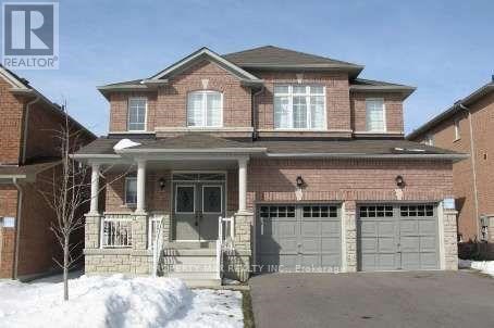 A large brick house with a garage door and a tree in front.