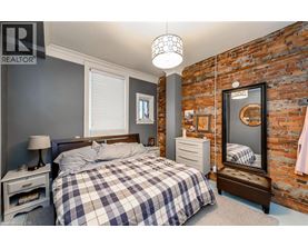 A bedroom with a bed, nightstand, and a brick wall.