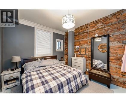 A bedroom with a bed, nightstand, and a brick wall.