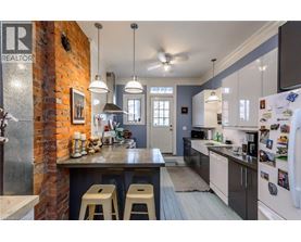 A kitchen with a brick wall and a counter with bar stools.