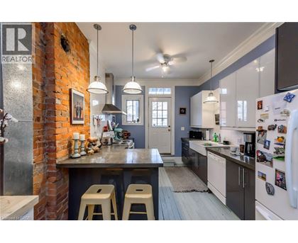 A kitchen with a brick wall and a counter with bar stools.