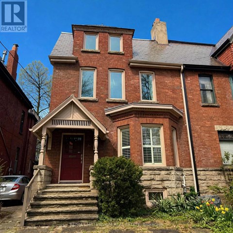 A red brick house with a car parked in front.