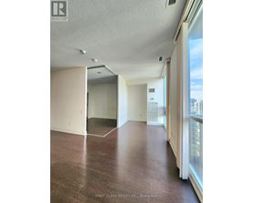 A room with wooden floors and white walls, with a window on the right side.