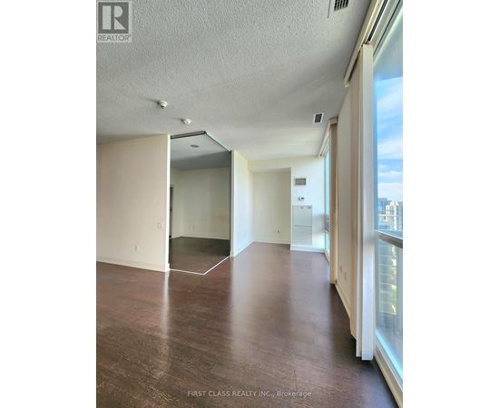 A room with wooden floors and white walls, with a window on the right side.