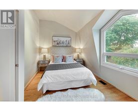 A bedroom with a large bed and a window overlooking trees.