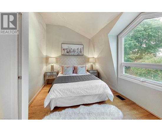 A bedroom with a large bed and a window overlooking trees.
