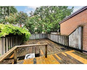 A wooden deck with a table and chairs is surrounded by a wooden fence and trees.