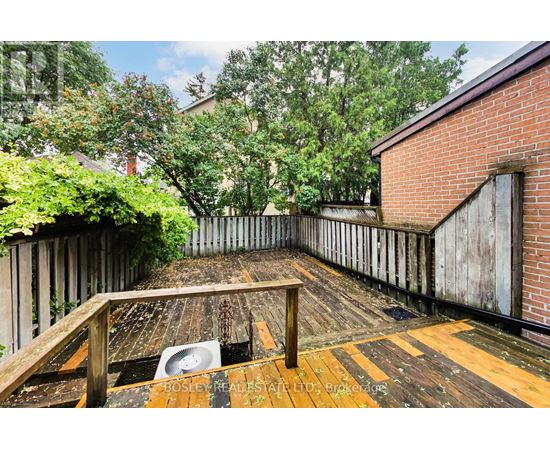 A wooden deck with a table and chairs is surrounded by a wooden fence and trees.