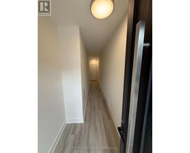 A hallway with wood flooring and white walls.