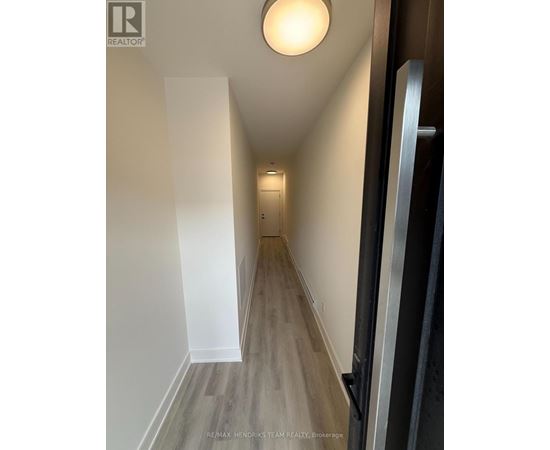 A hallway with wood flooring and white walls.