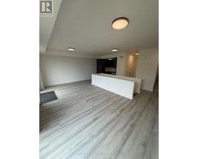 A spacious room with a white reception desk and grey flooring.