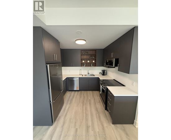 A modern kitchen with dark wood cabinets and stainless steel appliances.