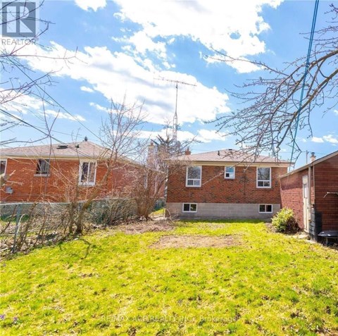 A grassy area in front of a brick building with a sign that says REALTOR.