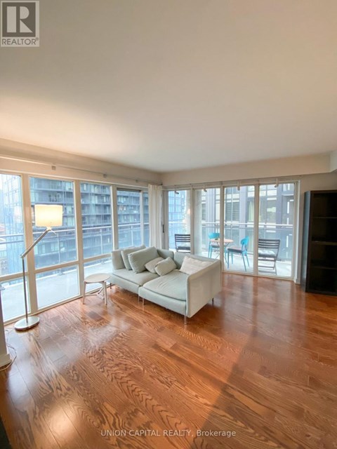 A living room with a white couch and wooden floors.