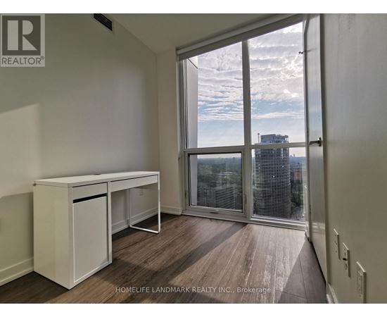 A room with a desk and a window overlooking a cityscape.
