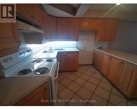 A kitchen with a white stove top oven and wooden cabinets.