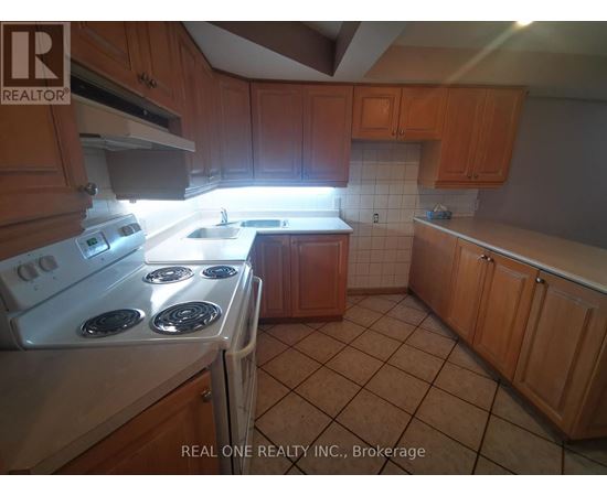 A kitchen with a white stove top oven and wooden cabinets.
