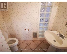 A bathroom with a toilet, sink, and wallpapered walls.