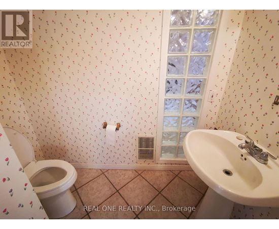 A bathroom with a toilet, sink, and wallpapered walls.