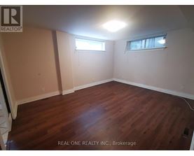 A room with wooden flooring and two windows.
