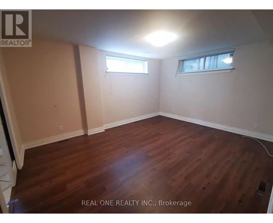 A room with wooden flooring and two windows.