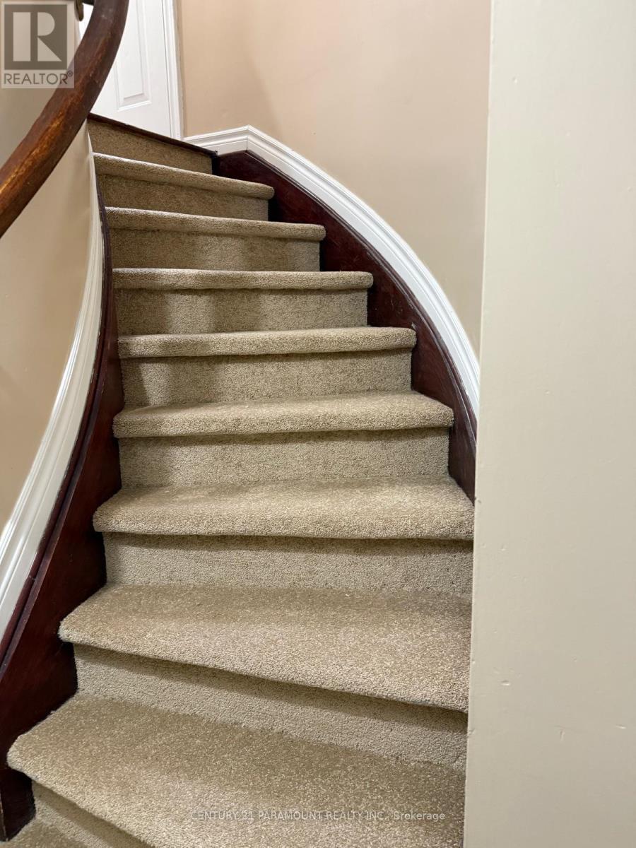 A beige carpeted staircase with a wooden handrail.