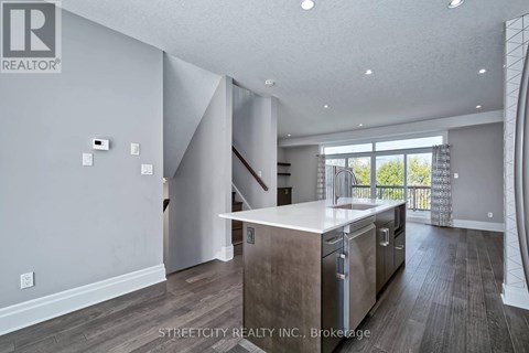 A modern kitchen with a refrigerator, oven, and sink.