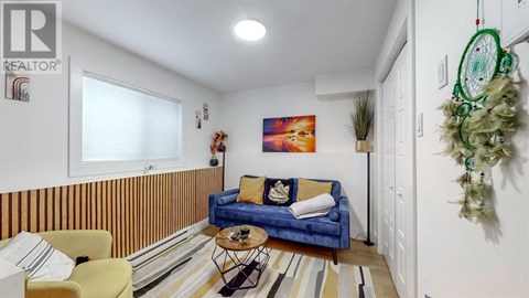 A living room with a blue couch and a painting on the wall.