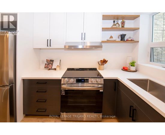 A modern kitchen with a stainless steel refrigerator, a stove with an oven, and white cabinets.