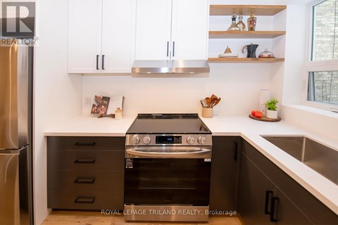 A modern kitchen with a stainless steel refrigerator, a stove with an oven, and white cabinets.
