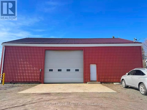 A red building with a white garage door and a car parked in front.