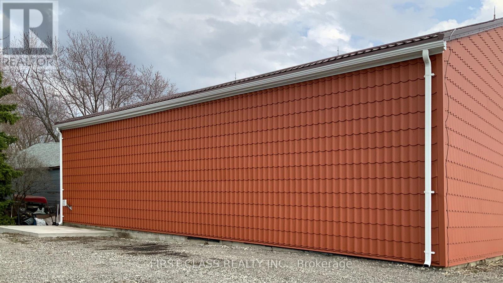 A red building with a grey roof and a white pipe on the side.