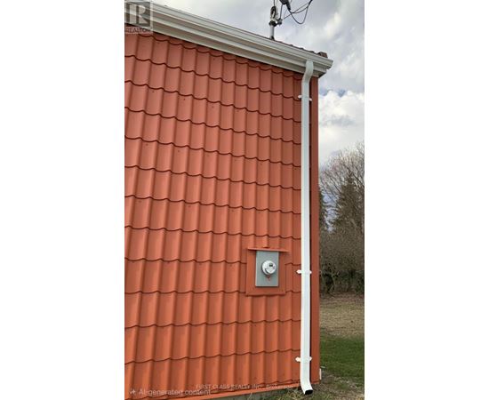 A red roof with a white pipe and a vent.