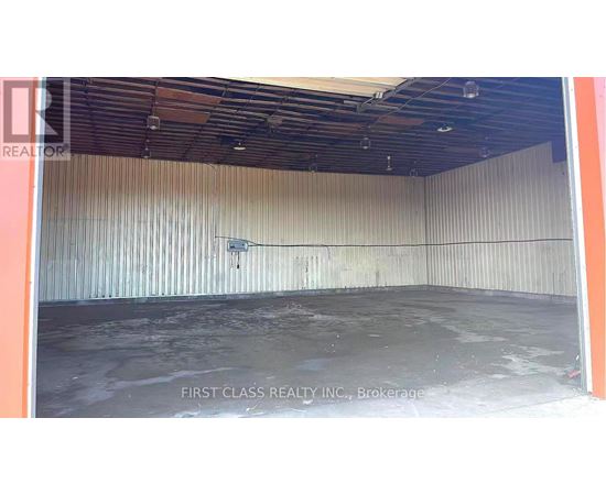 A large empty room with a concrete floor and a wall covered in corrugated metal sheets.
