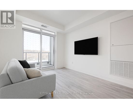 A living room with a grey couch and a flat screen TV mounted on the wall.