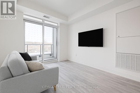 A living room with a grey couch and a flat screen TV mounted on the wall.