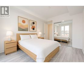 A bedroom with a large bed, two lamps, and a painting on the wall.