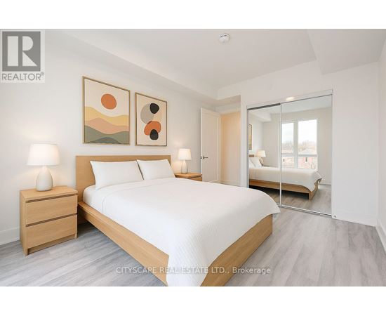 A bedroom with a large bed, two lamps, and a painting on the wall.