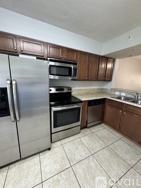 A kitchen with a stainless steel refrigerator and wooden cabinets.